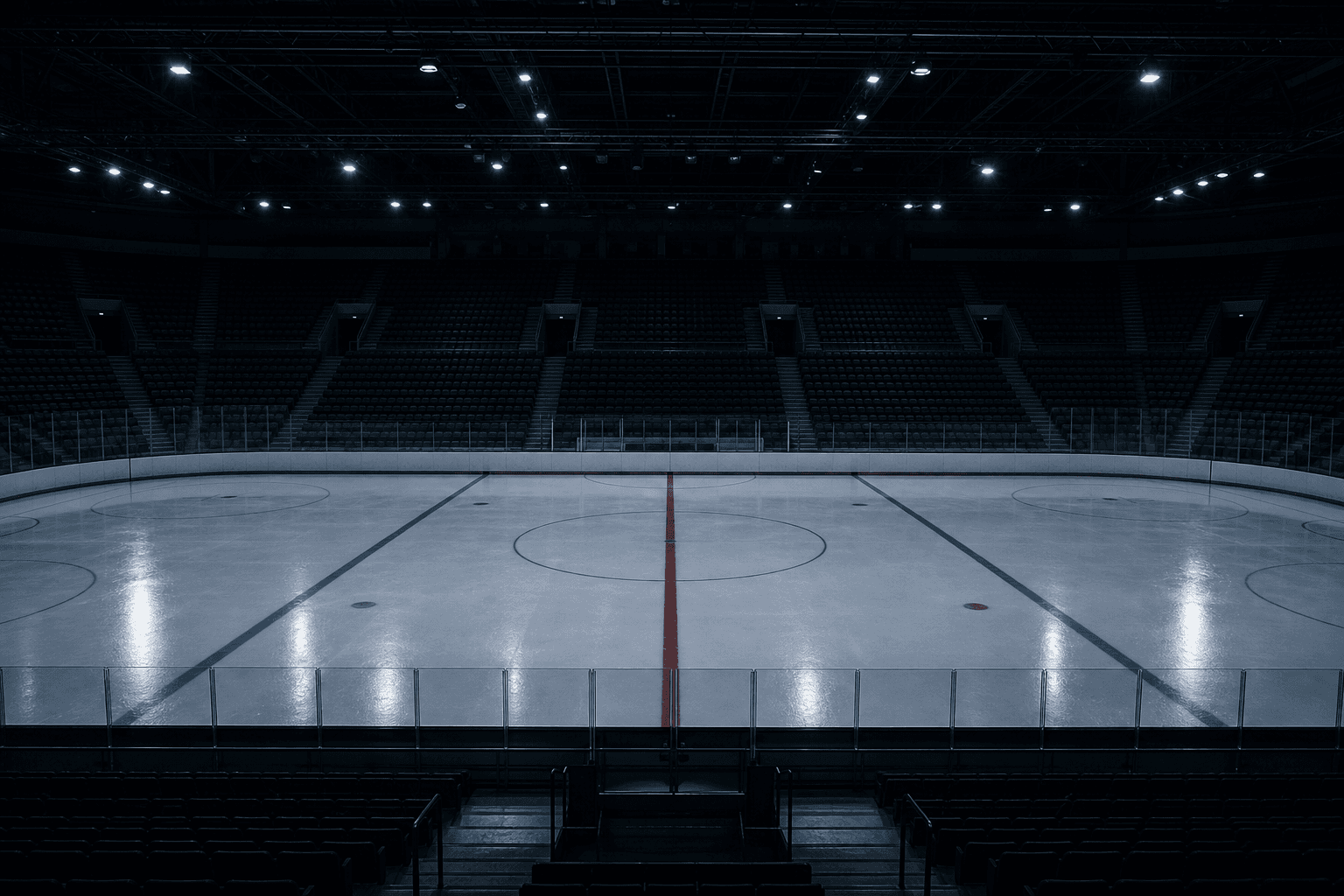 An empty hockey arena an hour before anyone arrives, lit only by work lights
